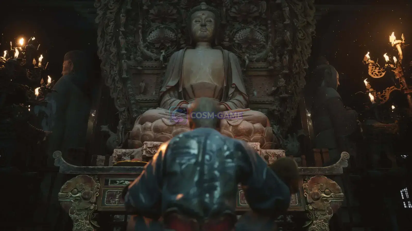 A figure kneels before a large seated Buddha statue inside a torch-lit shrine.