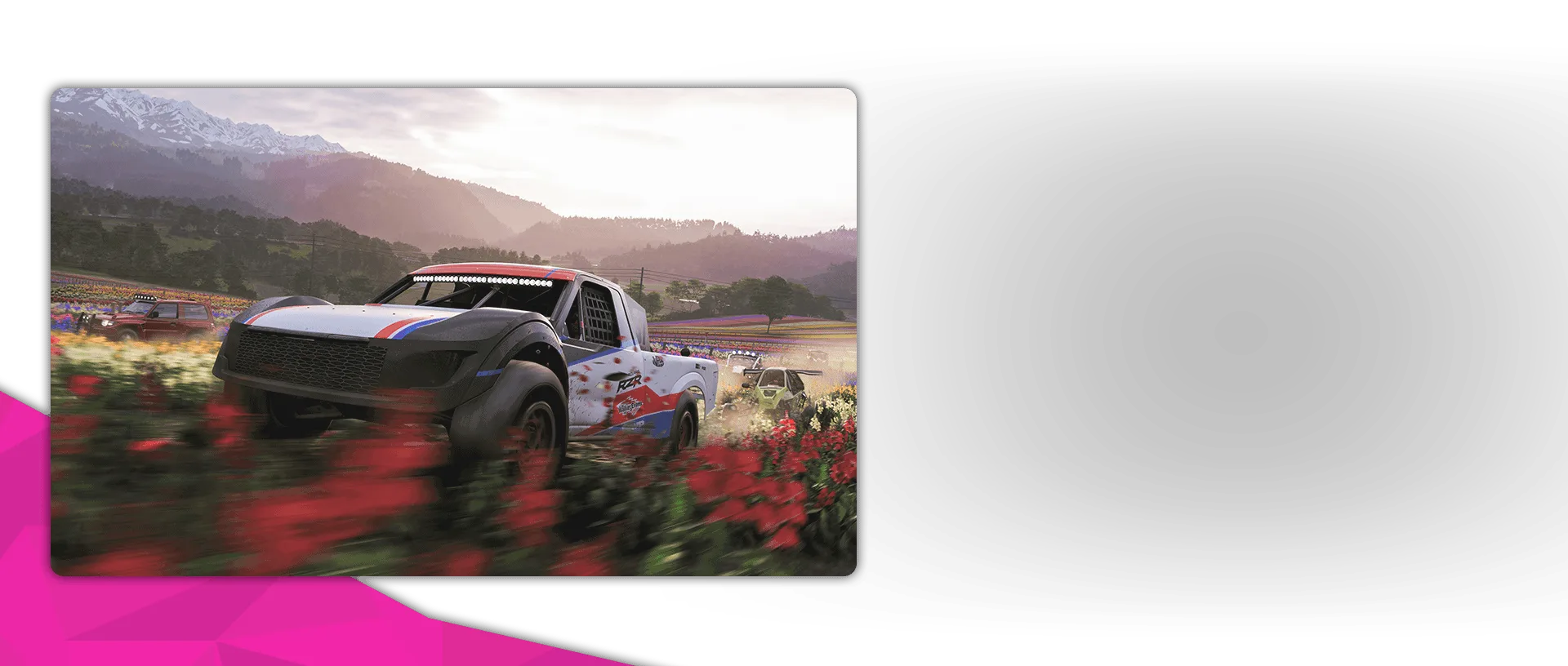 An off-road racing truck drives through a flower-covered field with mountains in the background.