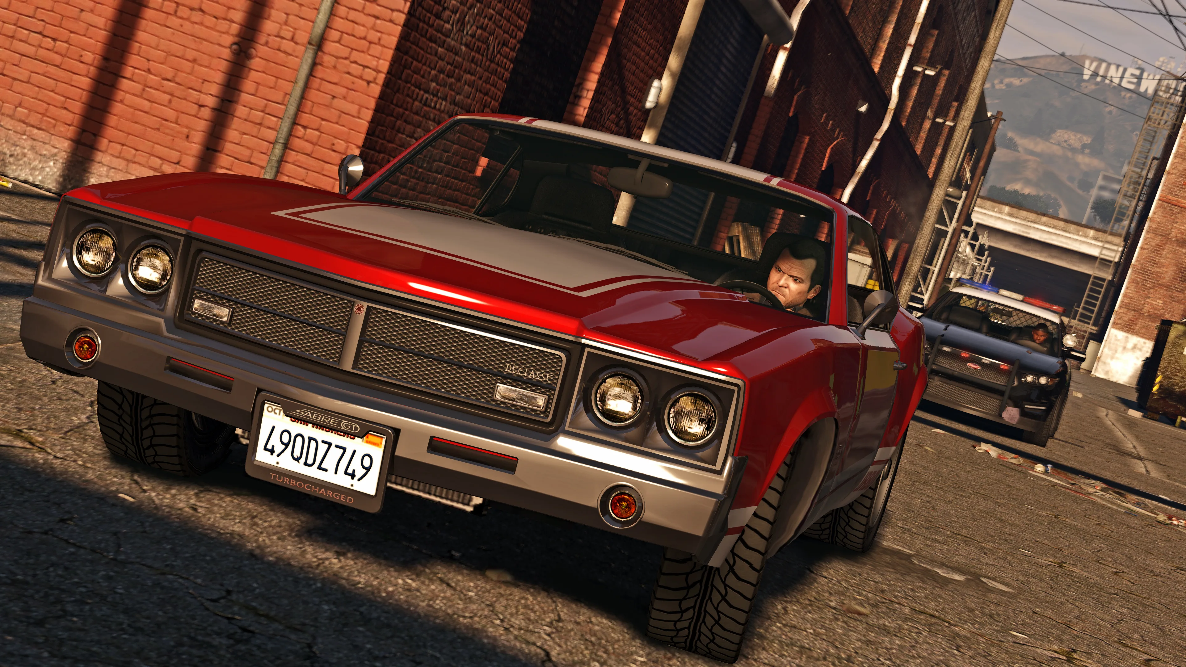 A red muscle car speeds through a brick-lined alley while another vehicle follows behind.