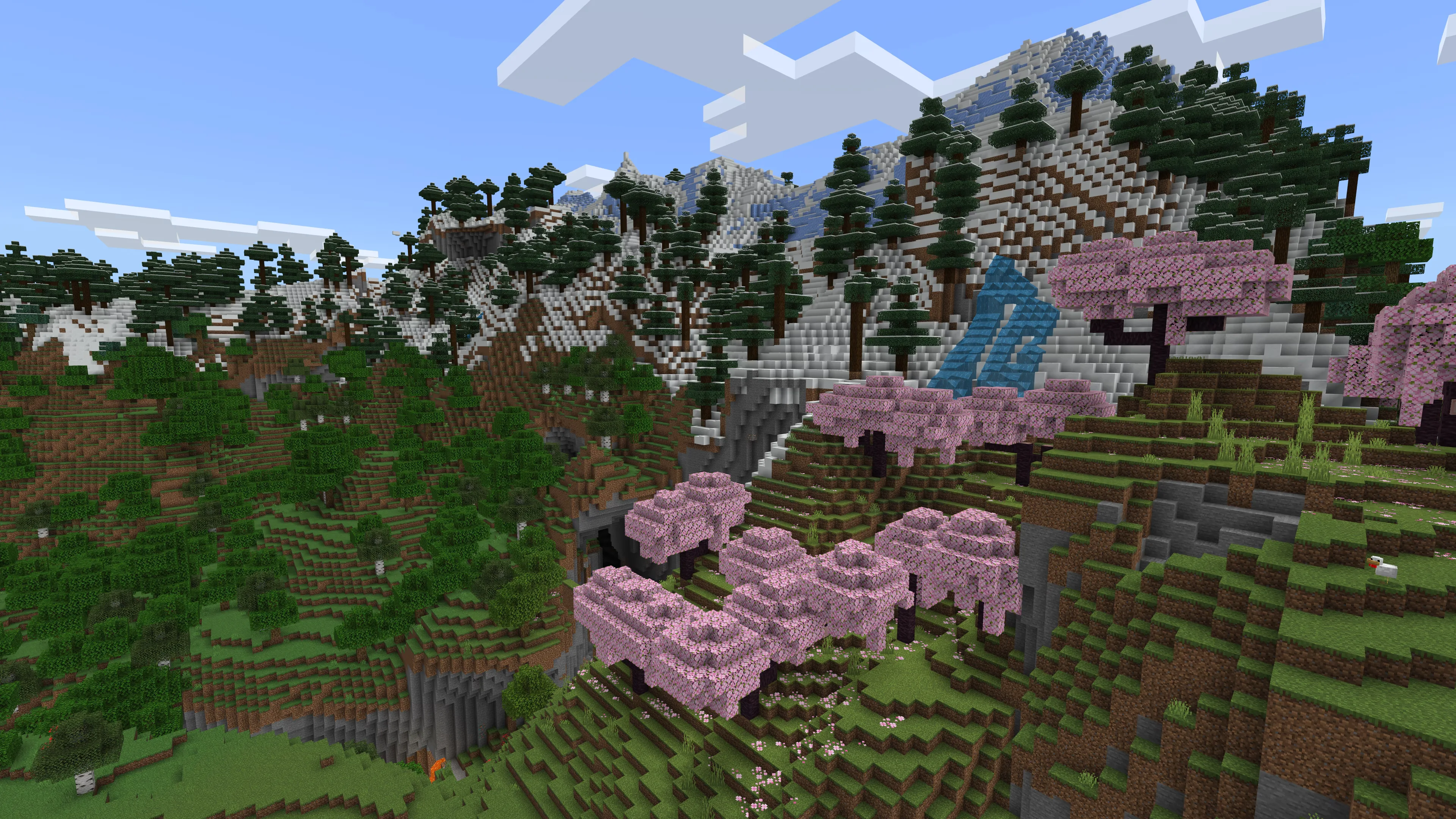 A snow-topped mountainside covered in oak, pine, and cherry trees under a clear sky