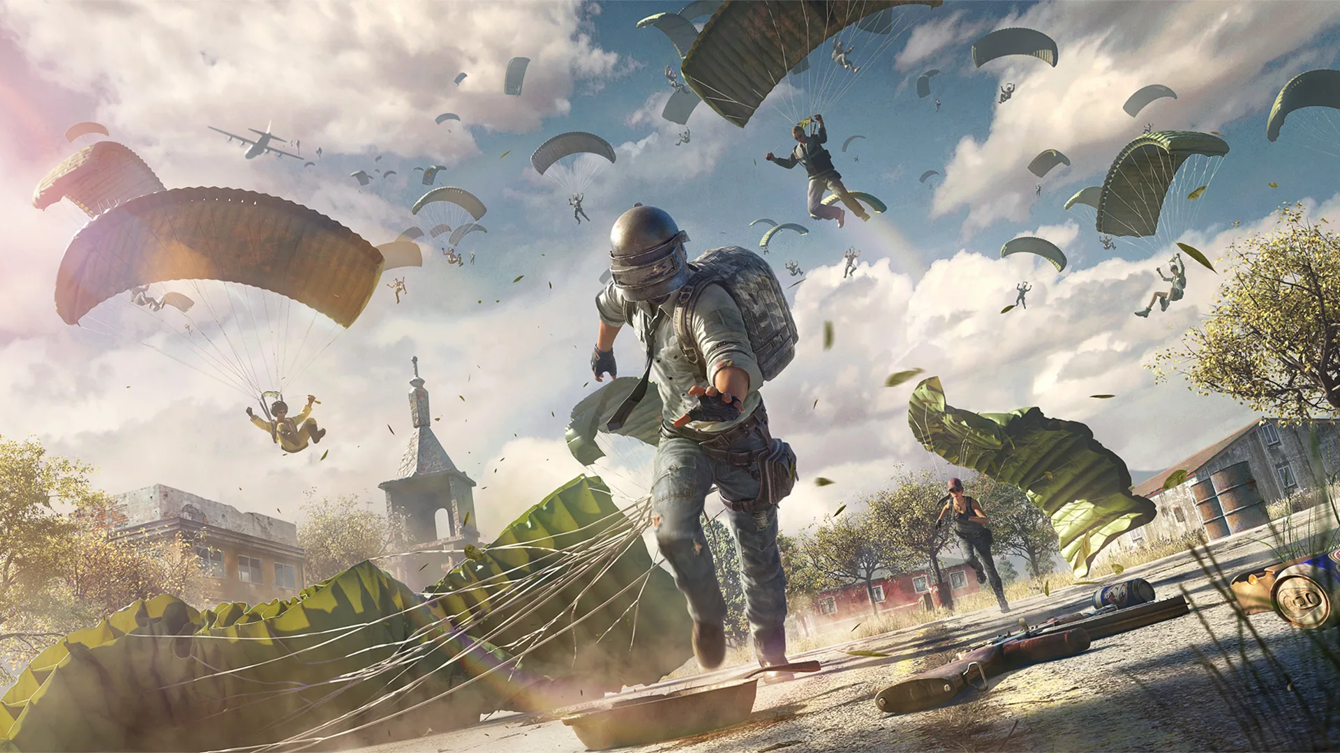 A helmeted PUBG Mobile combatant lands among dozens of parachuting players with weapons scattered across the battleground.